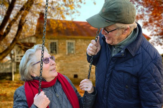 A happy elderly couple sharing a joyful moment on a swing in autumn setting.