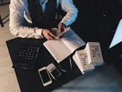 Businessman organizing finances with tech devices and cash on desk.